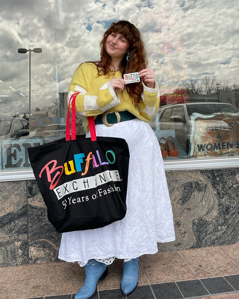 Smiling woman holds Buffalo Exchange gift card and tote bag