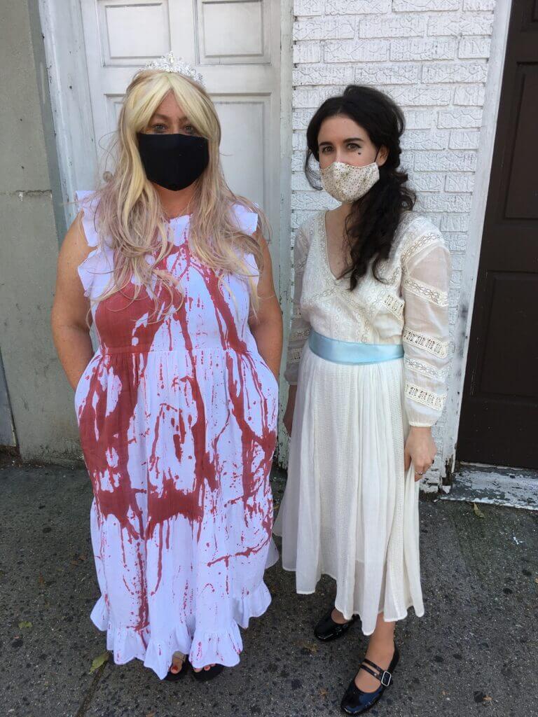 Two people in vintage gowns dressed like the characters Carrie and Baby Jane in long white vintage dresses.