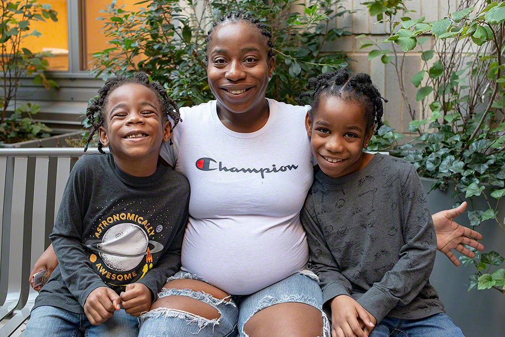 A Mother and their two children sitting down close to each other and smiling