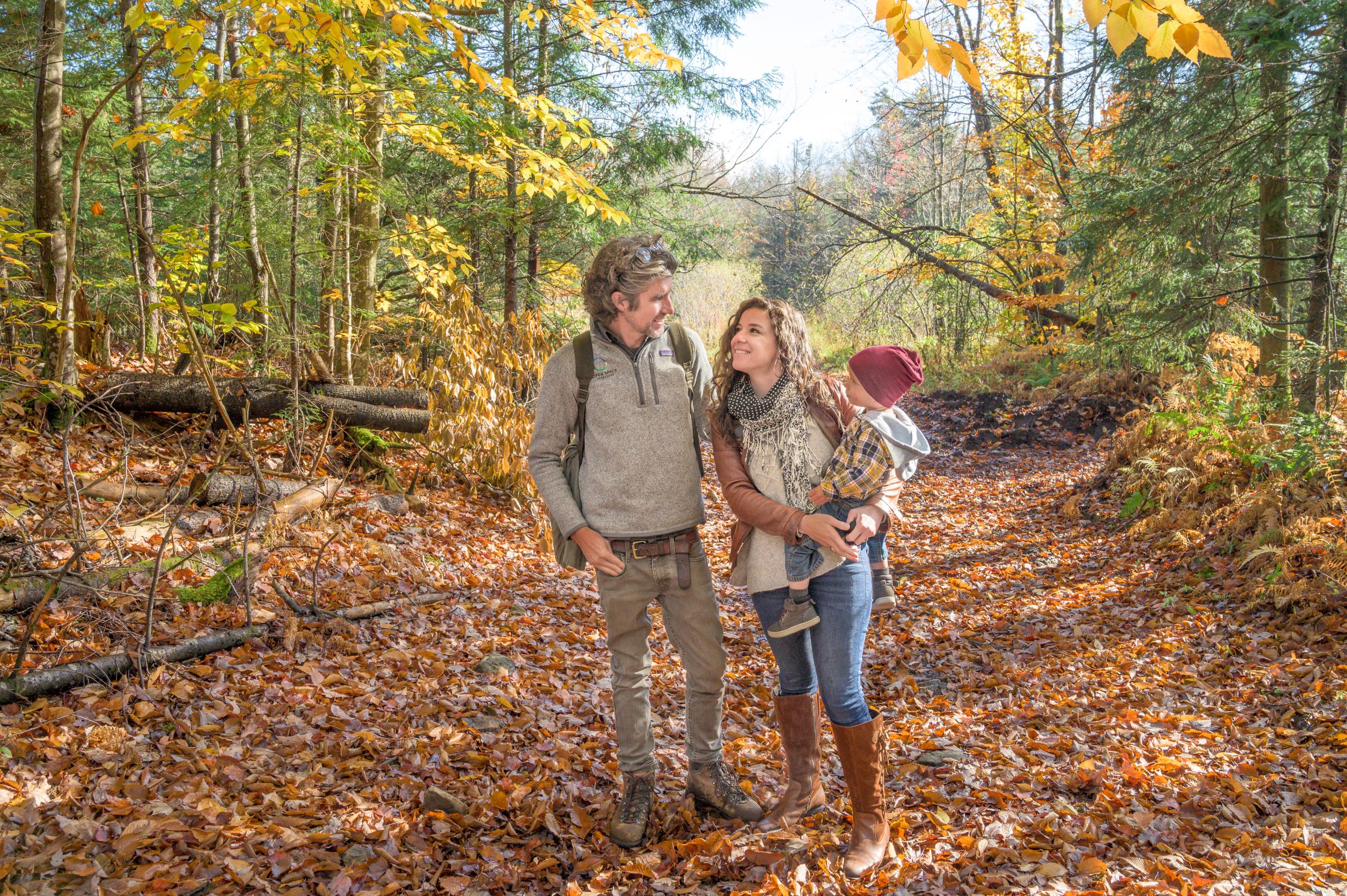 a couple and a toddler surrounded by trees