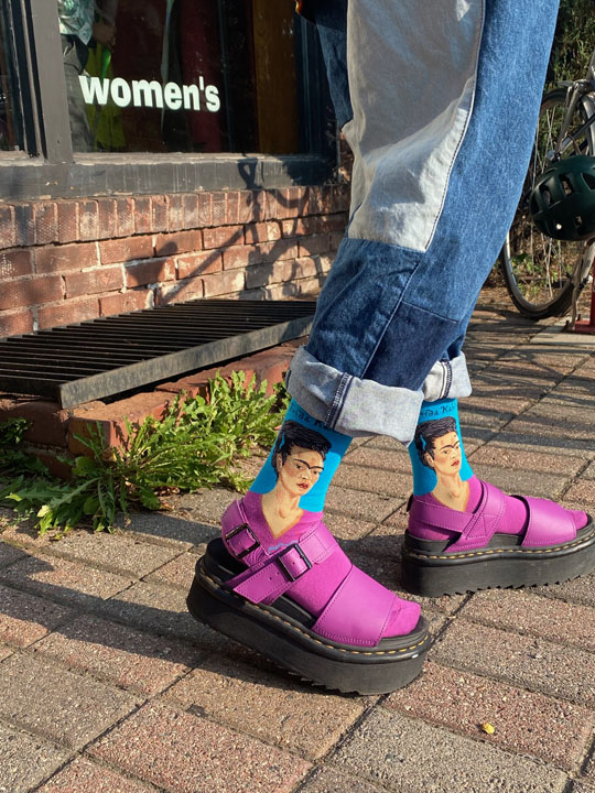 Close-up a person wearing Frida Kahlo socks and purple platform sandals