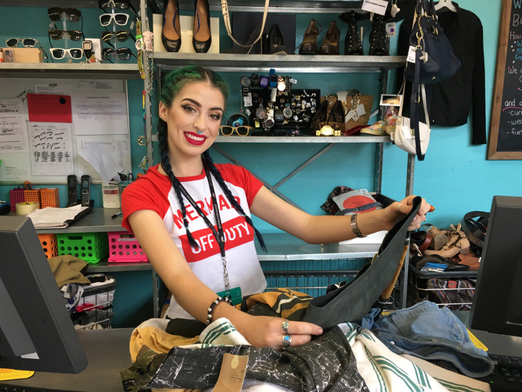 Buffalo Exchange Buyer posing behind the counter looking through clothes