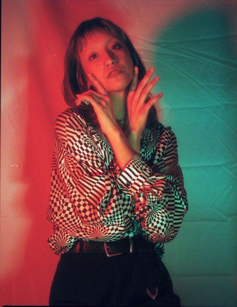 Dramatic photo of someone wearing psychedelic patterned shirt illuminated by red and blue lights