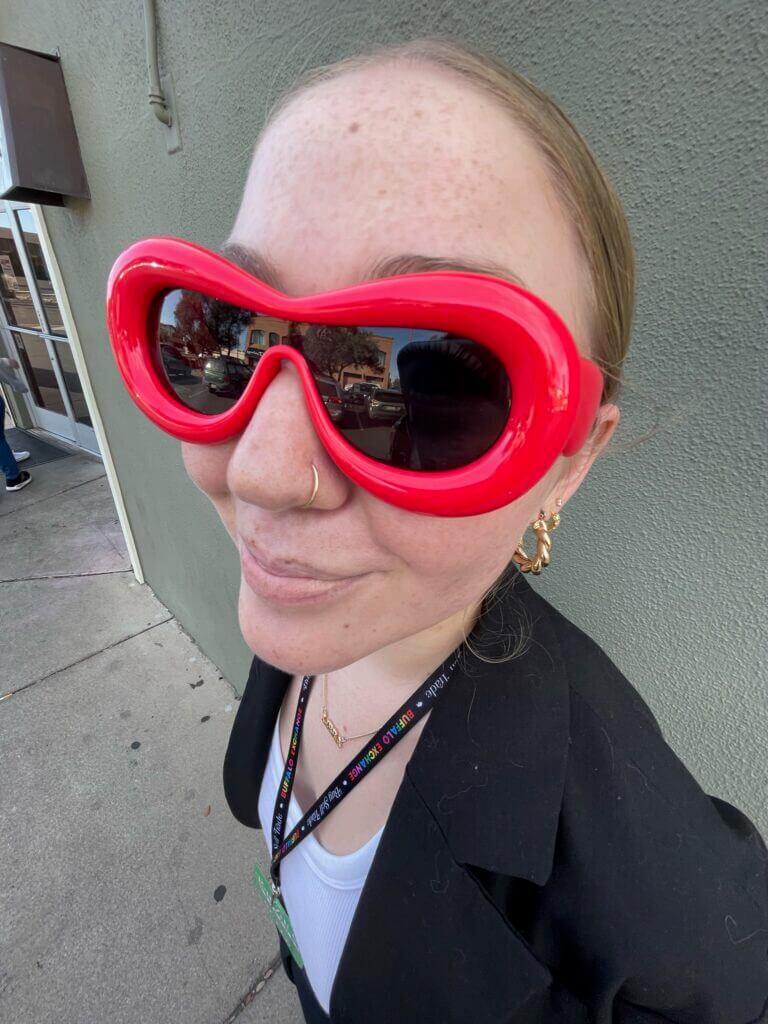 headshot of a person wearing round frame red sunglasses