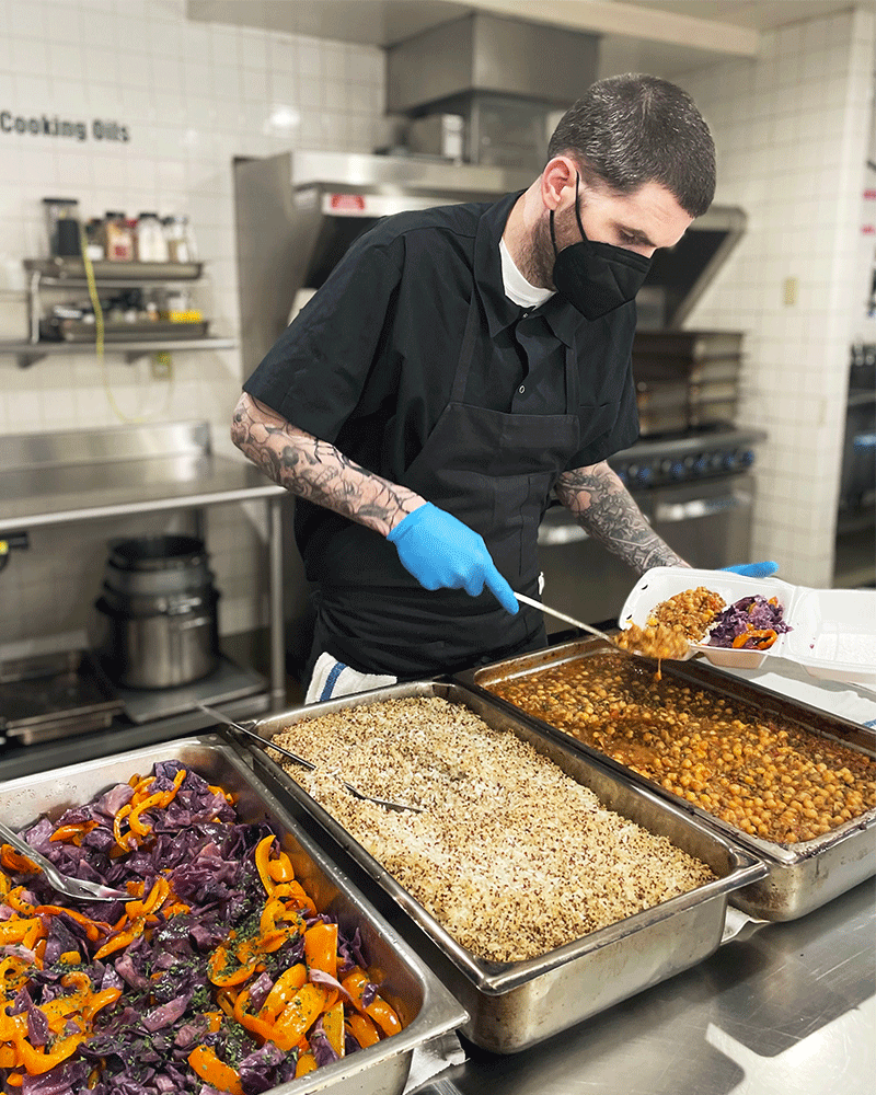 Volunteer Collin filling food containers from large trays