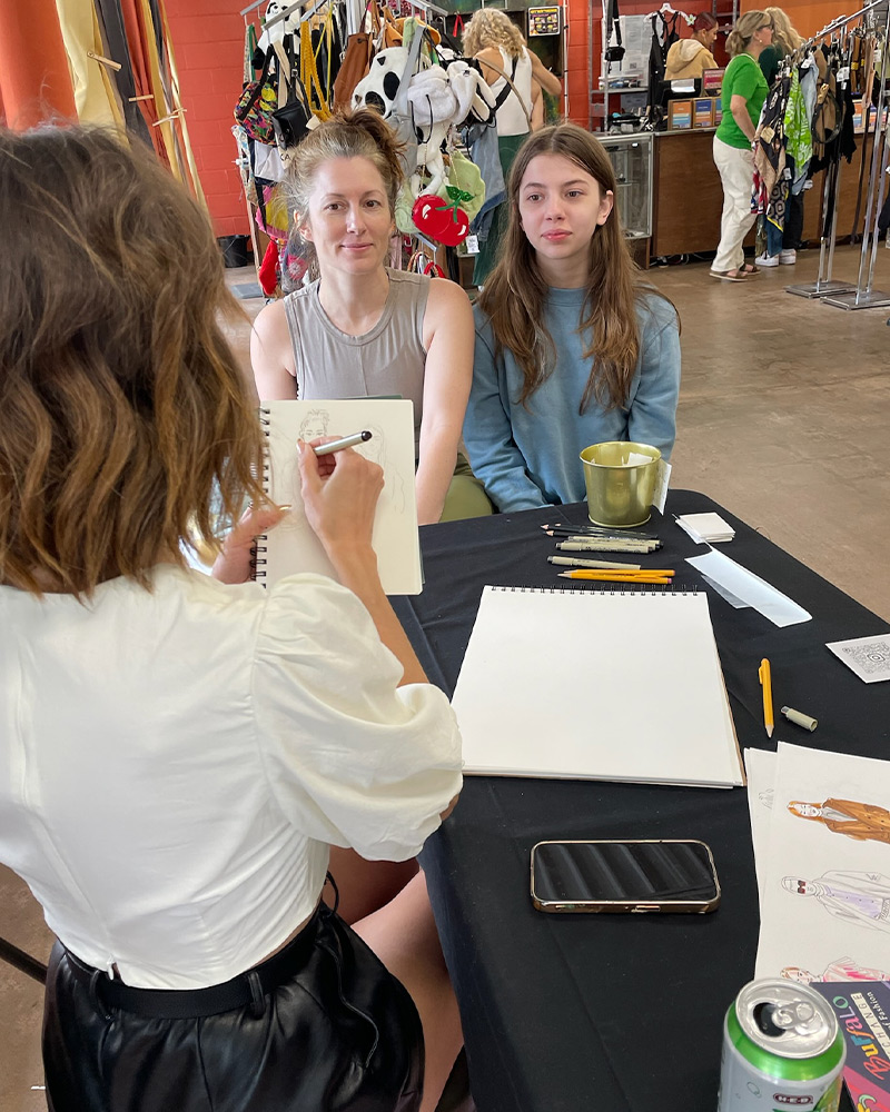 Two customers being drawn by an artist