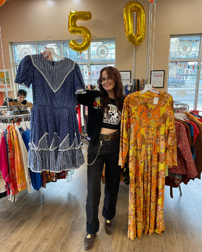 Employee holding up two dresses saved for the 50th