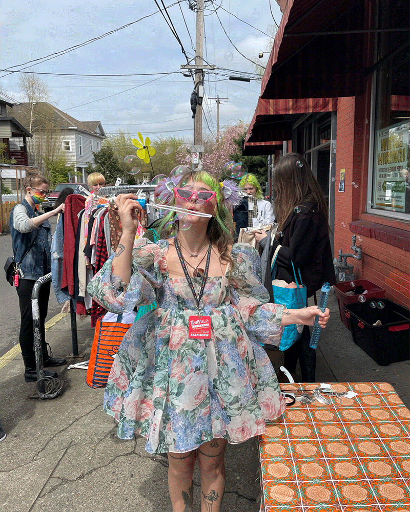 Buffalo Exchange Employee blowing bubbles in puffy dress outside store