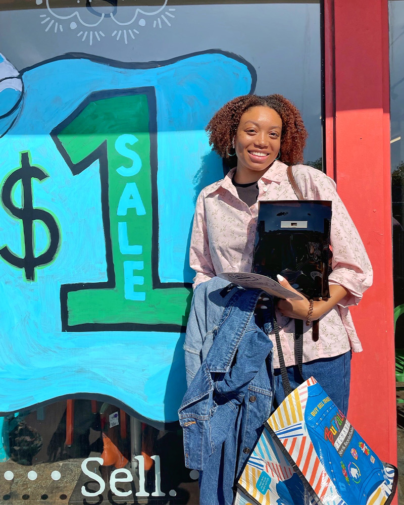 Customer by $1 sale sign Customer by $1 sale sign holding a bundle of clothing