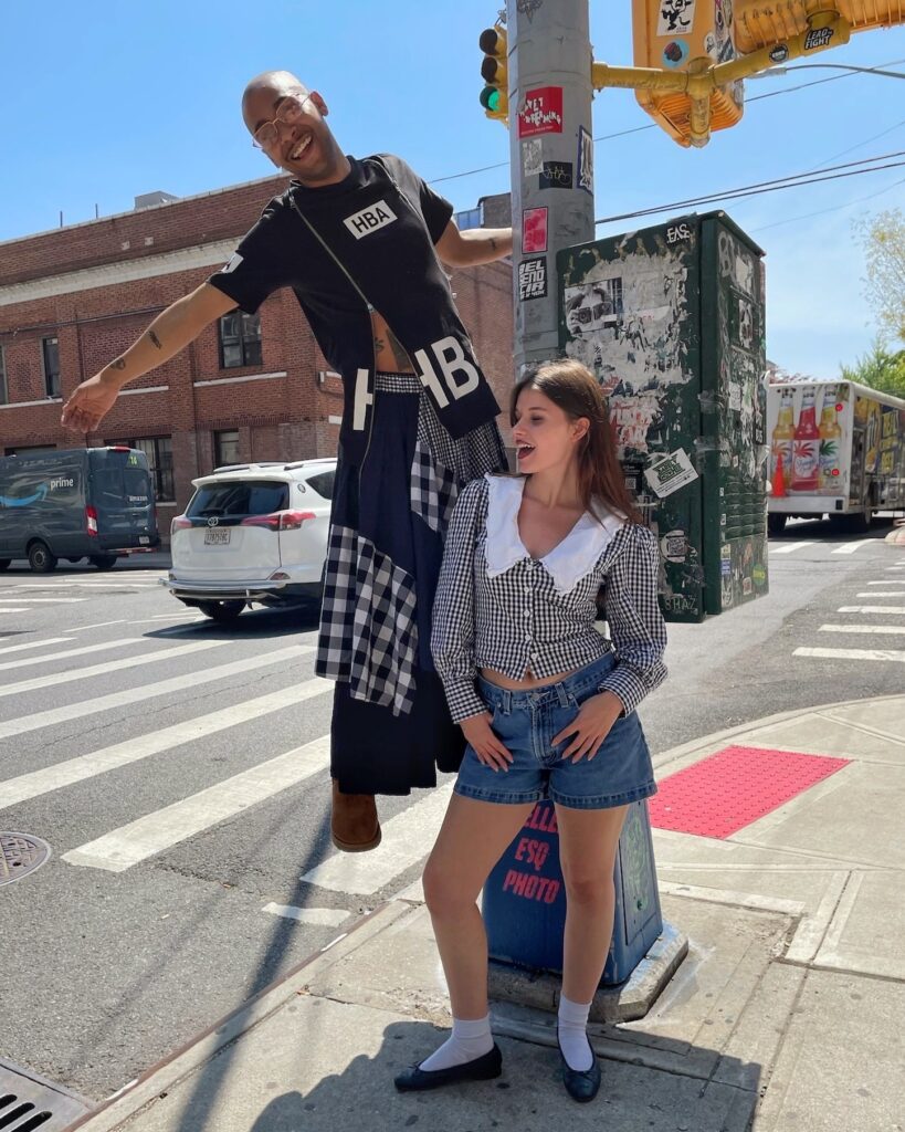 Two people standing at a crosswalk wearing monochromatic outfits with gingham plaid