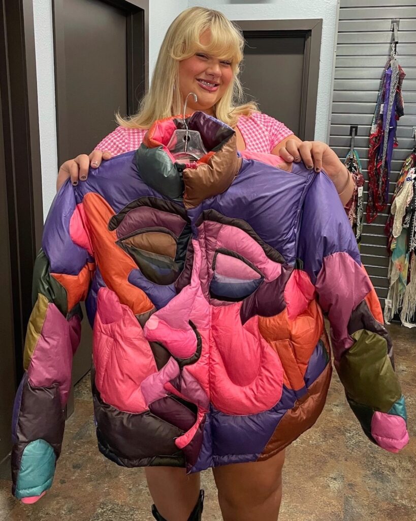 Person holding KidSuper pink and purple quilted puffer jacket