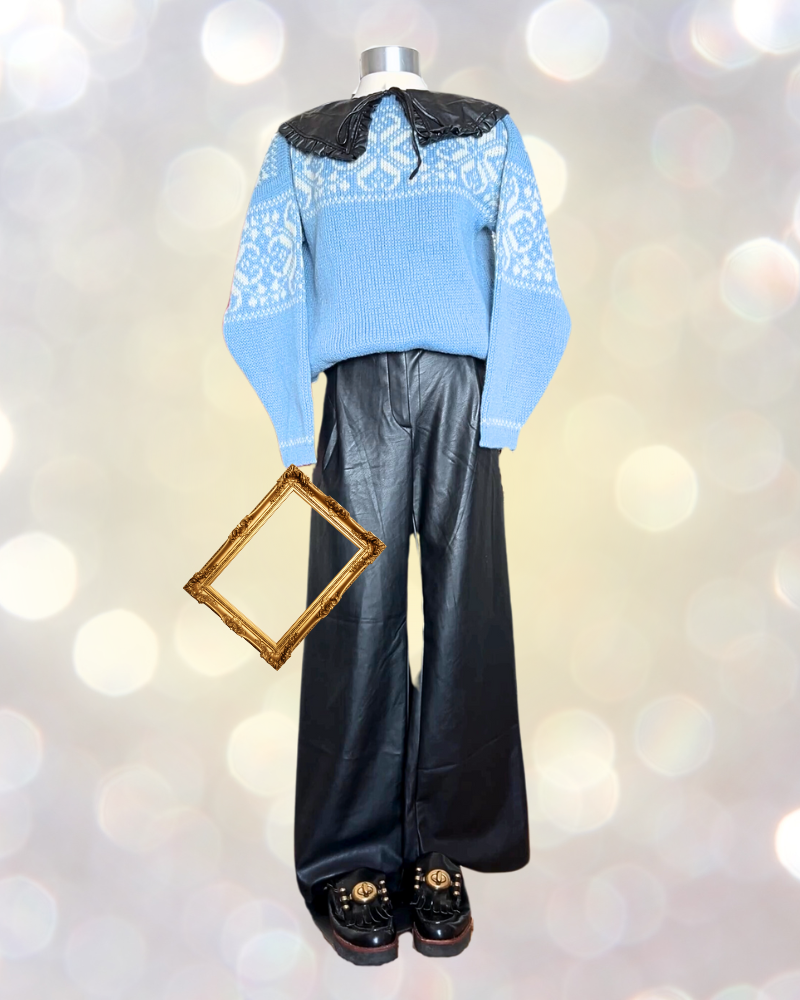 Mannequin holding picture frame wears blue Fair Isle sweater and leather pants