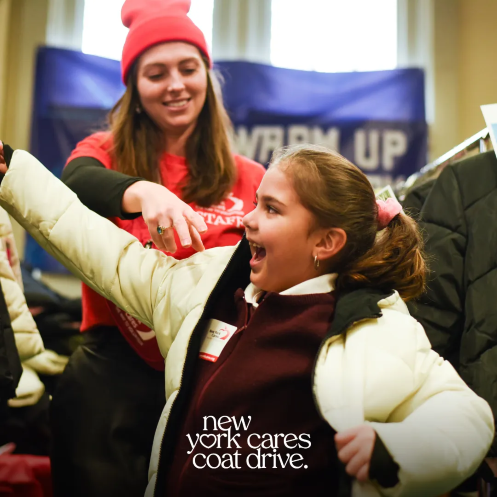 New York Cares volunteer helping child put on a coat