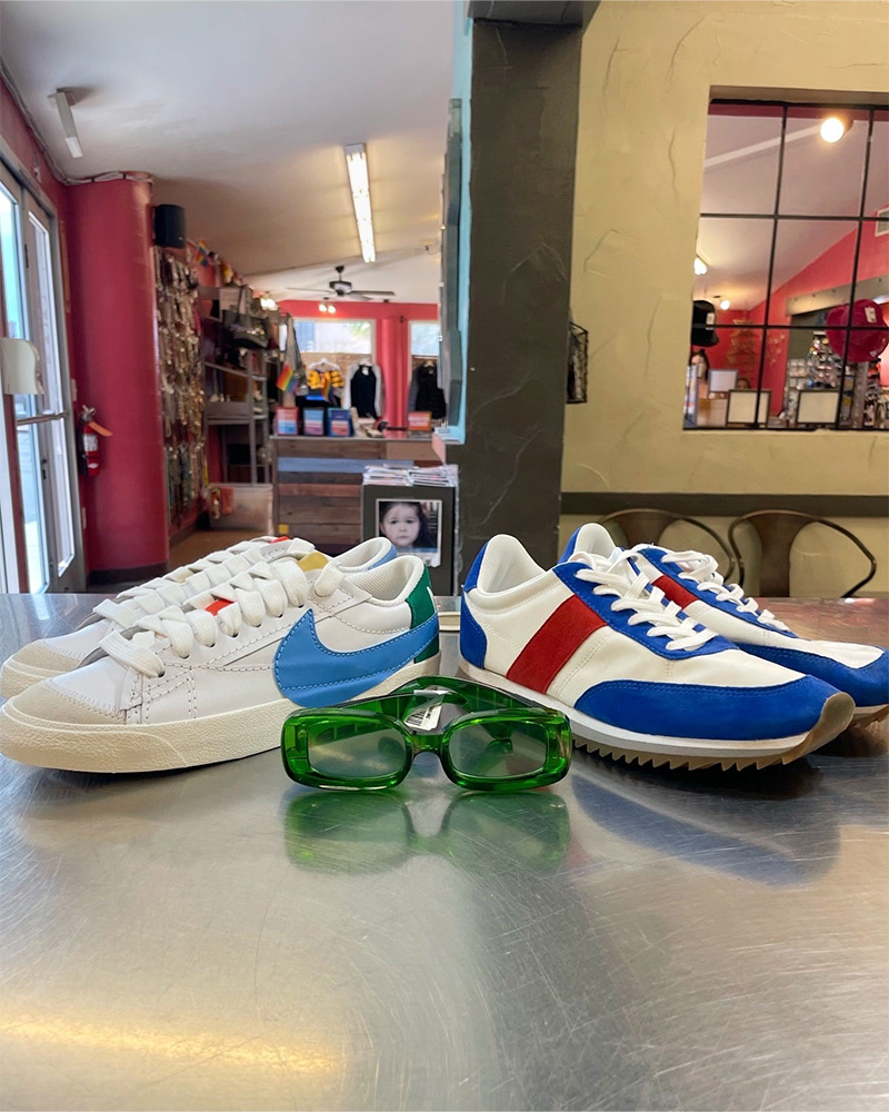 Blog-11-Edited Two pairs of Nike sneakers and a pair of green sunglasses sit on top of a silver counter