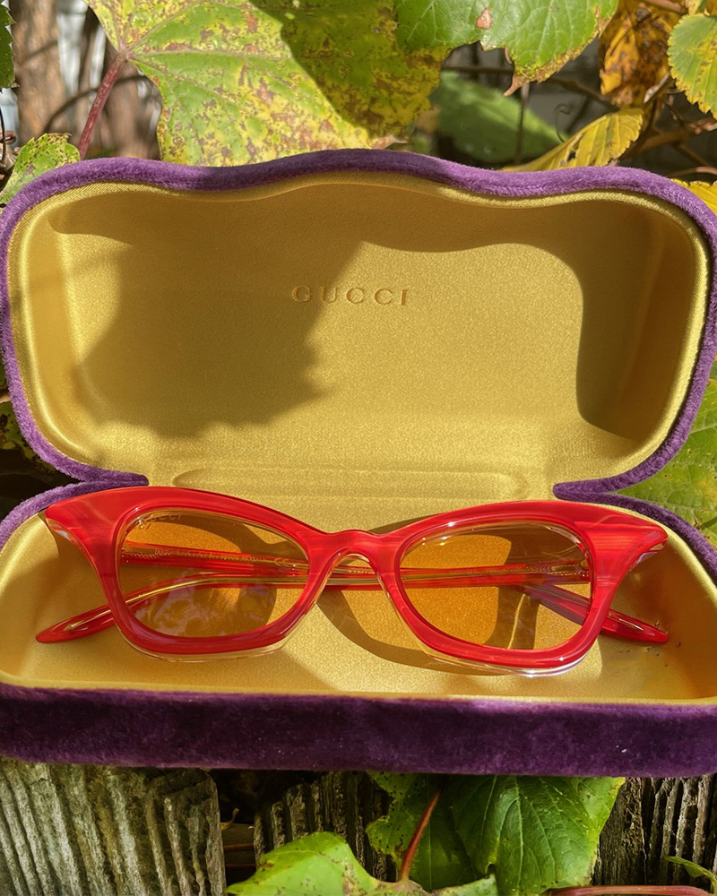Blog-23-Edited A pair of translucent red Gucci cateye glasses in sit in their yellow and purple case