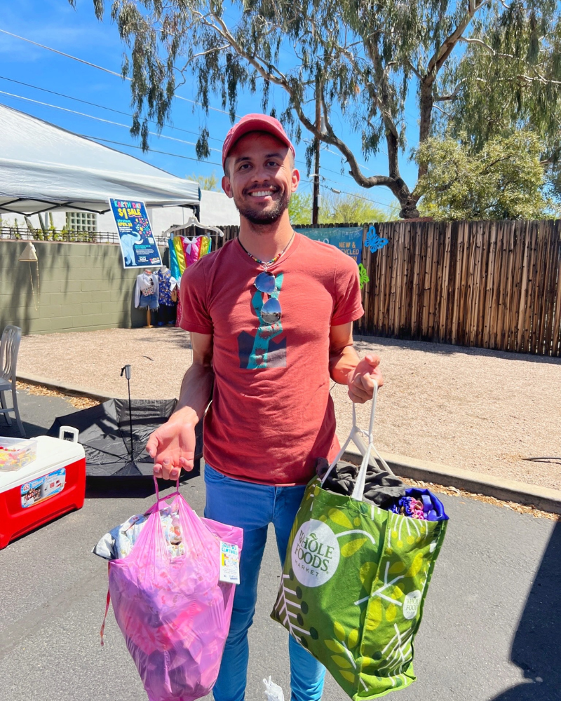 eday blog pic 2 resized a man standing in a parking lot smiles while holding to bags full of clothing