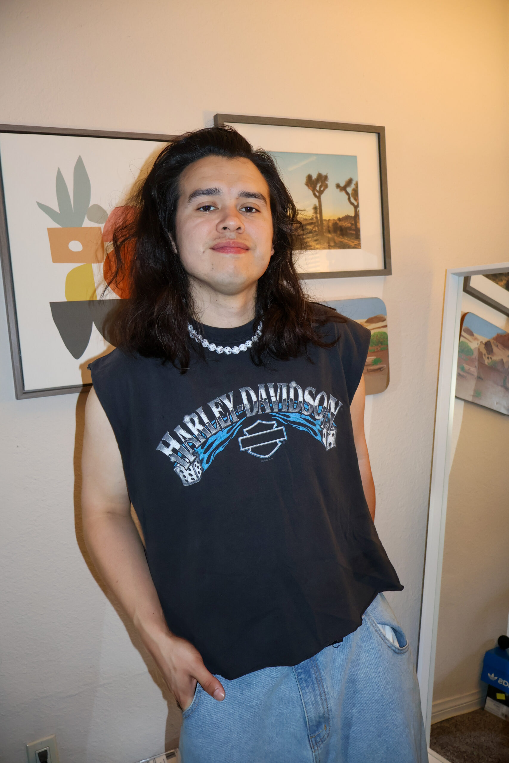Buffalo Exchange employee Cesar standing in front of various paintings