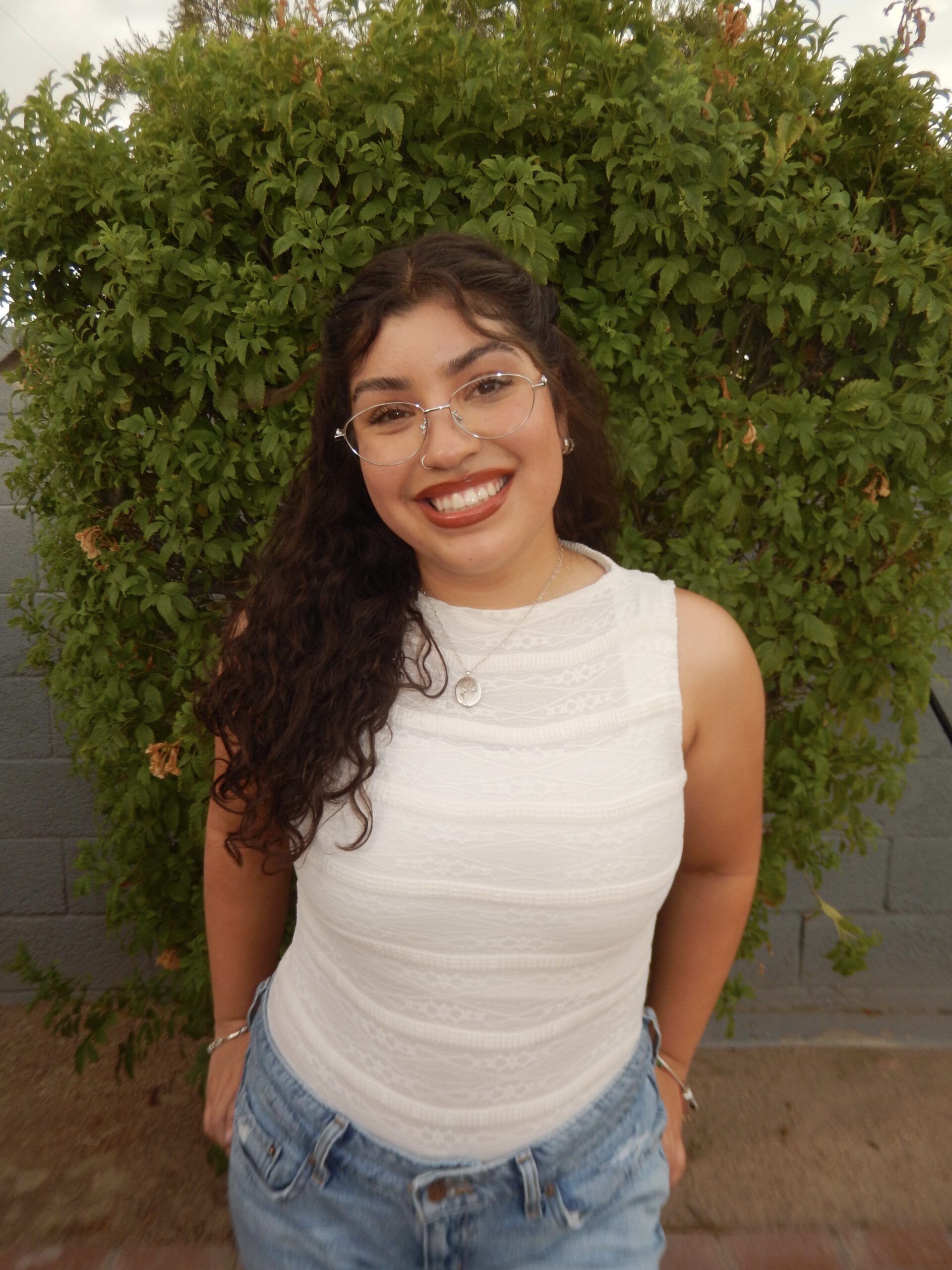 Buffalo Exchange employee Raquel standing in front of a green hedge