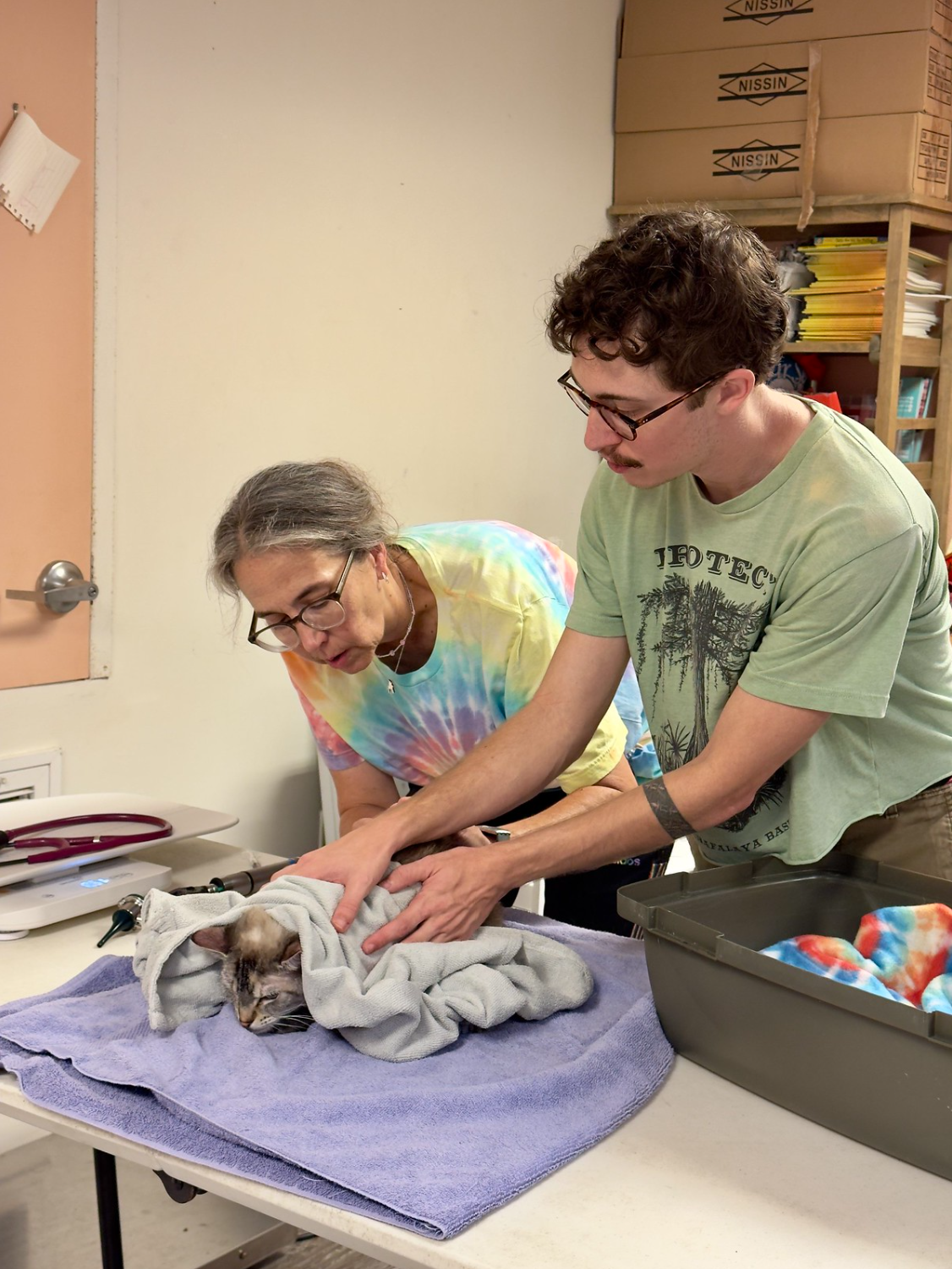 Inner Pup members wrapping a cat in a blanket